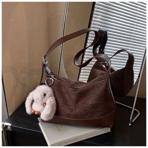 Detail of dark brown pleated hobo bag with white plush rabbit charm and silver metal zipper