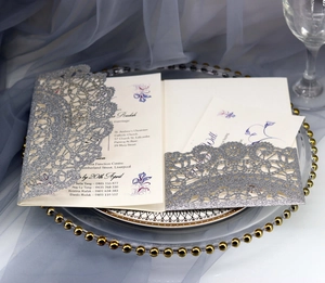 Close-up of silver glitter laser-cut wedding invitation on luxury decorative glass tray