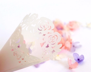Macro view of white laser-cut rose lace paper cones for wedding confetti and dried petals