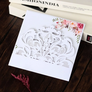 Detail of laser-cut white wedding invitation with elegant floral lace and scroll patterns