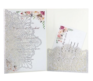 Macro detail of laser-cut glitter invitation with floral wedding card and RSVP insert