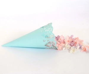 Close-up of light blue laser-cut paper cone with hollow floral and heart patterns for weddings