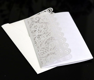 Detail of laser-cut white lace wedding invitation with intricate floral hollow pattern