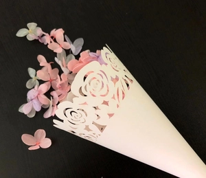 Detailed laser-cut white wedding confetti cones with floral pattern and dried petals
