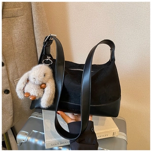 Detail of black pleated shoulder bag with leather strap and cute rabbit plush charm