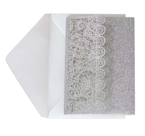 Macro shot of silver glitter wedding invitation with laser-cut floral lace and white envelope