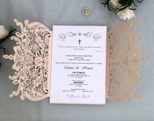 Detail of laser-cut rose patterns on elegant pale pink wedding invitation with insert