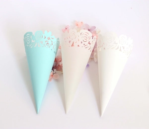 Detailed laser-cut rose patterns on blue and white paper confetti cones for wedding party
