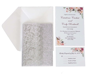 Macro view of silver glitter laser-cut lace invitation set with floral detail