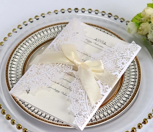 Detail of laser-cut wedding invitation with cream ribbon and Valentine card in a tray
