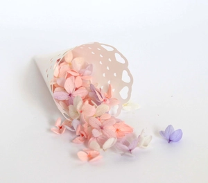 Close-up of pastel hydrangea petals scattered from a white heart cutout paper cone