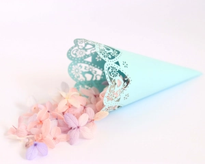 Detail of light blue laser-cut wedding confetti cone with delicate floral hollow patterns