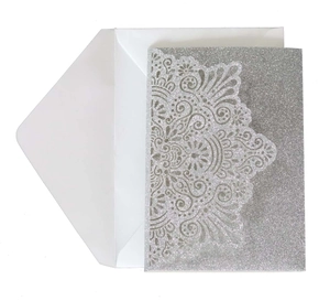 Detailed laser-cut silver glitter invitation card with a matching white envelope