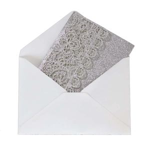 Detail of laser-cut silver glitter wedding invitation with elegant floral lace pattern