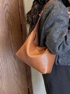 Brown faux leather shoulder bag with lychee texture shown on model in grey coat