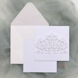Detail view of laser-cut white lace wedding invitation set with envelope and inner card