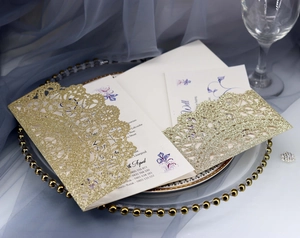 Detailed close-up of laser-cut glitter gold wedding invitation with elegant lace patterns