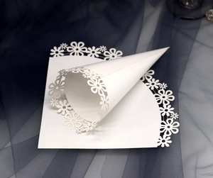 Detail showing white laser-cut lace paper cones for wedding confetti with floral pattern