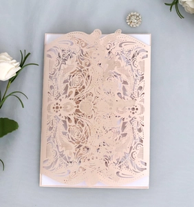 Macro shot of laser-cut rose floral pattern on a pink wedding invitation card