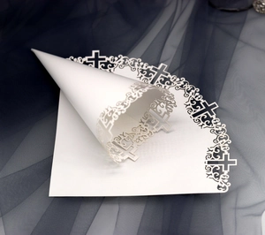 Detailed laser-cut white wedding paper cone featuring a religious cross pattern design