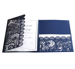Detail showing the intricate laser-cut floral pattern of the navy blue wedding invitation
