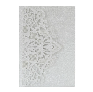 Macro detail of laser-cut silver glitter wedding invitation with intricate vine patterns