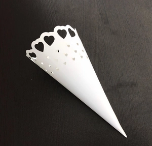Detail of white paper wedding confetti cone with heart-shaped lace edges and cutouts