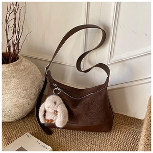 Detail of dark brown pleated hobo bag featuring a cute plush bunny charm and zip closure