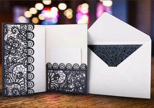 Detail of laser-cut lace invitation card with elegant floral patterns on blue cardstock