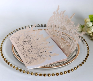 Close-up of laser-cut floral pink wedding invitation with intricate rose patterns