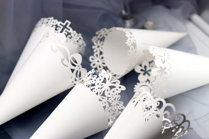 Detail of white laser-cut wedding petal cones with butterfly and floral hollow patterns