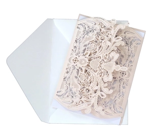 Detail of laser-cut floral pattern on pink wedding invitation with envelope