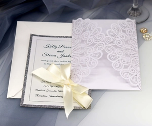 Elegant laser-cut wedding invitation set with silver glitter border and white ribbon