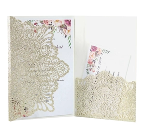 Macro detail of laser-cut gold glitter wedding invitation with floral inner card