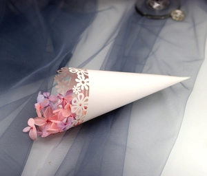 Close-up of laser-cut white floral paper cone filled with pink and purple dried flowers