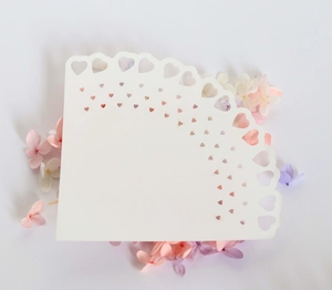 Close-up of laser-cut heart pattern on white lace wedding confetti cone paper