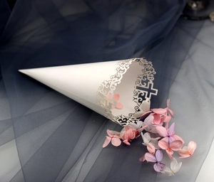Laser-cut white paper wedding cone with intricate lace cross patterns and flower petals