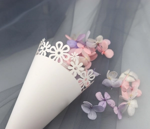Macro detail of white laser-cut floral cone with dried petals for wedding confetti