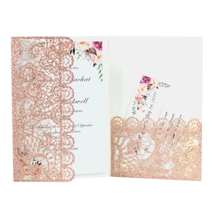 Close-up of laser-cut lace pattern wedding invitation with rose gold glitter finish