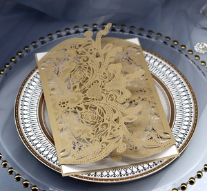 Elegant gold laser-cut invitation card with floral patterns on white decorative tray