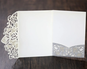 Detailed laser-cut wedding invitation featuring beige lace folds and silver glitter inner pockets