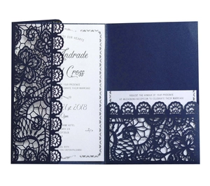 Macro detail of laser-cut floral lace pocket wedding invitation in navy blue and white
