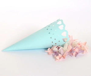 Close-up of light blue laser-cut heart pattern paper cone with delicate wedding flower petals