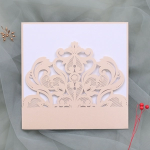 Close-up of cream laser-cut lace wedding invitation with floral patterns and gold accents