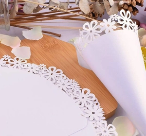 Detailed view of white laser-cut floral paper cones for wedding confetti and celebrations