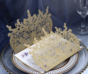 Elegant gold laser-cut floral wedding invitation card set on a stylish dinner plate