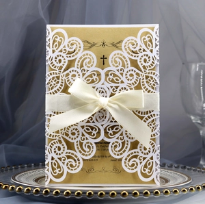 Laser cut invitation with white filigree sleeve, kraft insert, and silk bow on a table