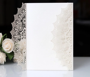 Detailed laser cut lace pattern on white engagement invitation card with floral accents