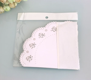Detail of laser-cut white lace paper cones with rose pattern for DIY wedding decor