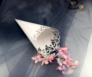 Close-up of white paper wedding cone with laser-cut hollow heart pattern edges